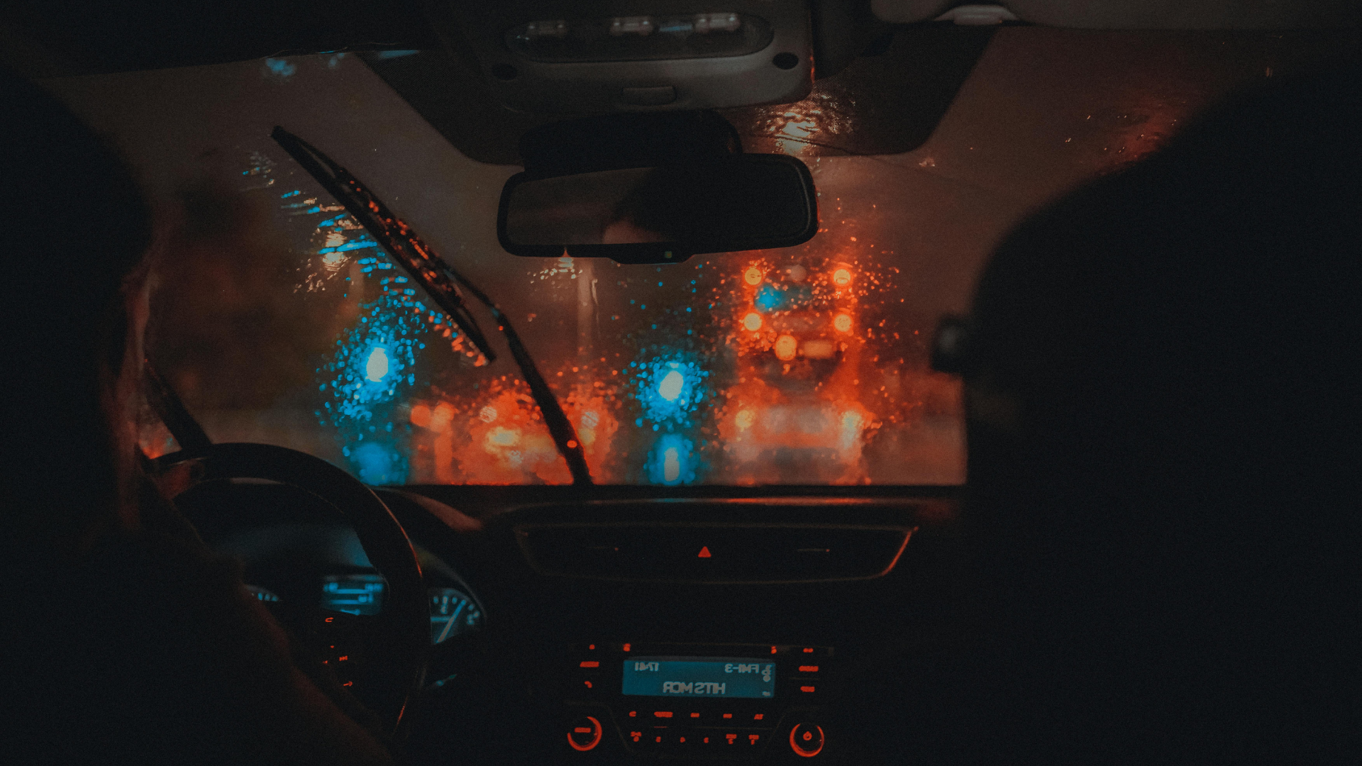 Personas manejando de noche con lluvia con un tractocamión frente a ellos